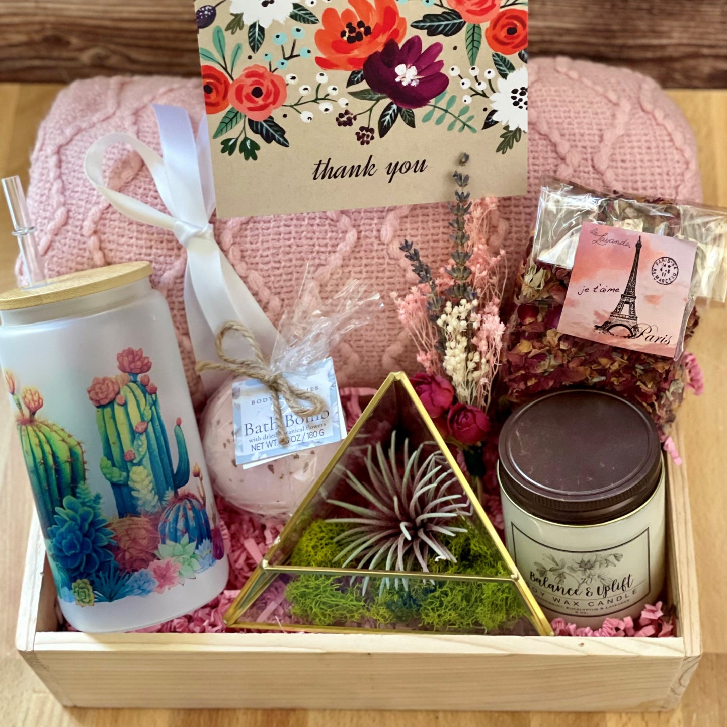 This gift box is chucked full of pretty items, includes throw blanket in blush pink, designer drinking cup with straw, handmade soy candle balance and calm, a terrarium with airplant, and more.