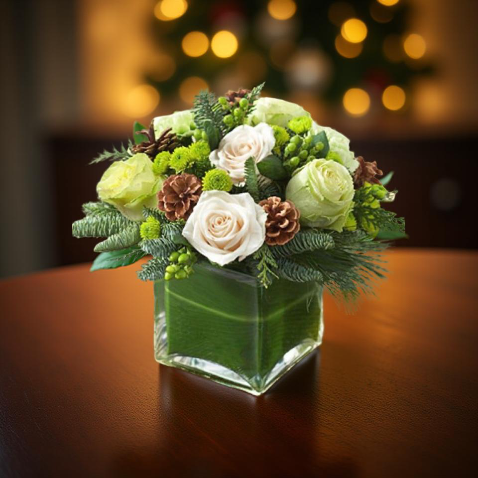 Christmas flower arrangement green pine, white roses, little green button mums, green berries and pine cones in a modern square vase.